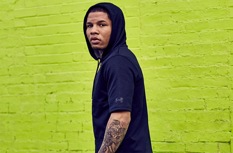 Man wearing black short sleeve pursuit hoodie standing in front of bright green wall