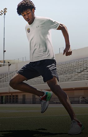 A guy doing footwork drills on a field wearing a customized white UA Tech T-Shirt made through UA Xp