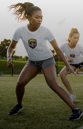 2 women training on a field wearing customized short sleeve shirts with school logo made through UA 