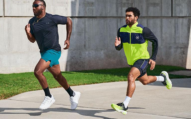 Two men in athletic gear sprinting down a paved road 