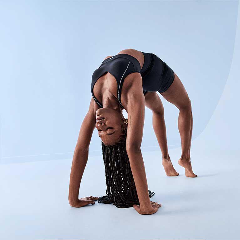 A woman in a black sports bra and shorts performing a wheel pose 